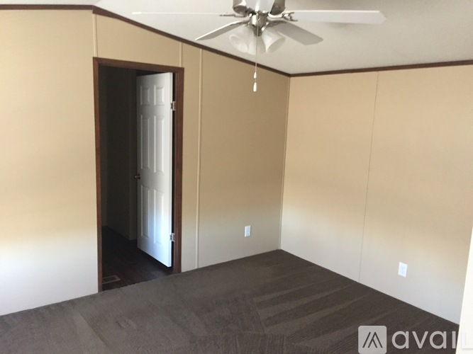 A room with a fan and a doorway leading to another room.