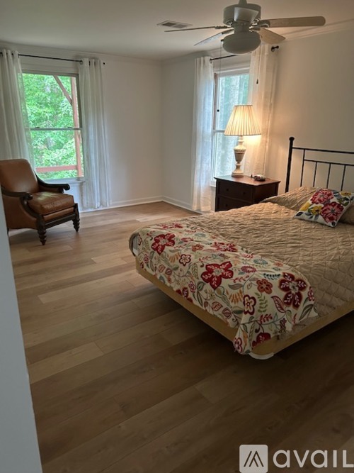 A bedroom with a bed, chair, and lamp.