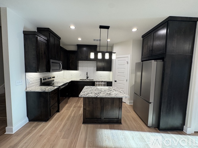 A kitchen with black cabinets and a marble island.