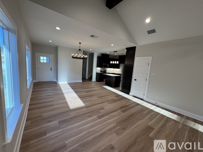 A spacious room with wooden flooring and a chandelier.