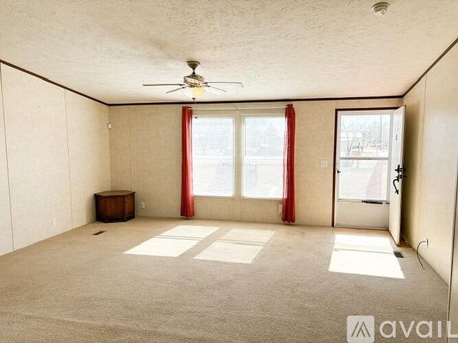 A room with a ceiling fan and a door leading to another room.