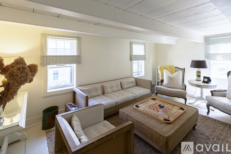 A living room with a couch, chair, and a table with a lamp on it.
