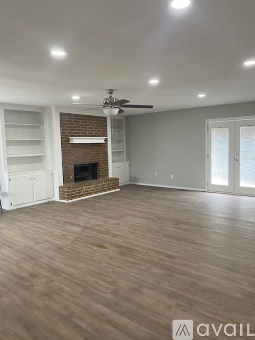 A spacious room with a fireplace and a ceiling fan.