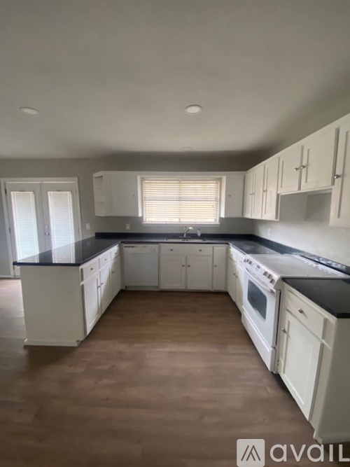 A kitchen with white cabinets and black countertops.