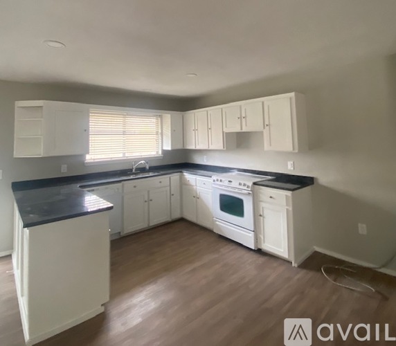 A kitchen with white cabinets and black countertops.