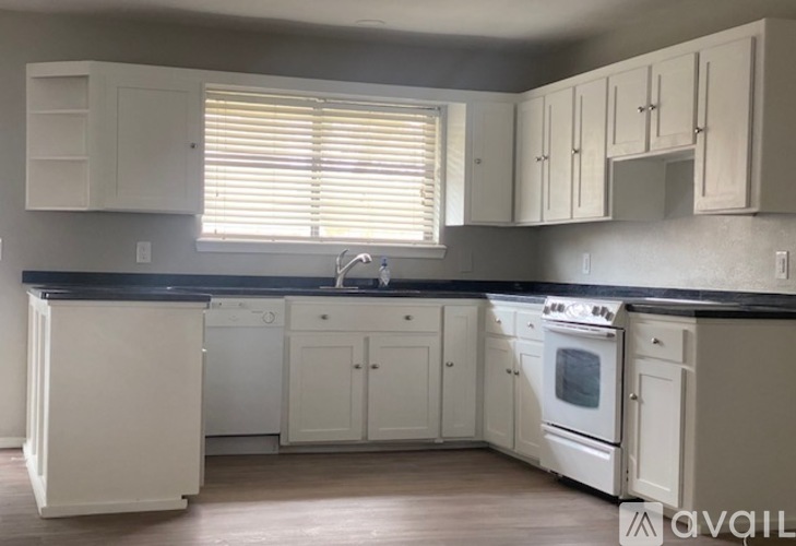 A kitchen with white cabinets and a black countertop.