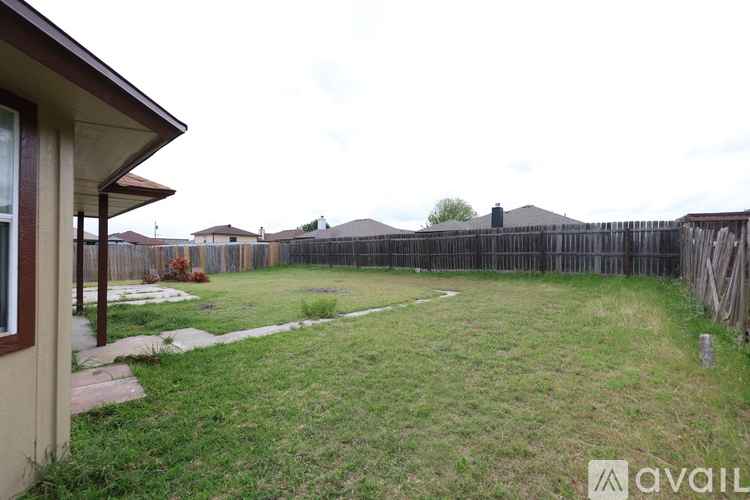 A backyard with a wooden fence and a grassy area.