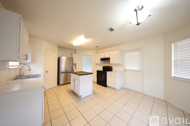 A kitchen with white cabinets and a black fridge.