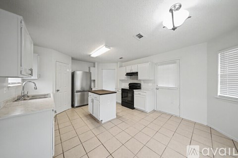 A kitchen with white cabinets and a black fridge.