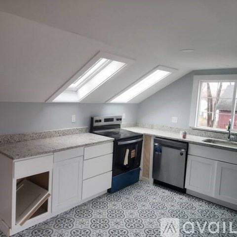 A kitchen with a black oven and a black trash can.