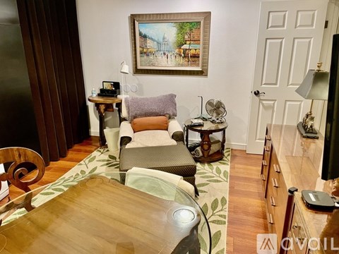 A living room with a couch, a chair, a coffee table, and a painting on the wall.