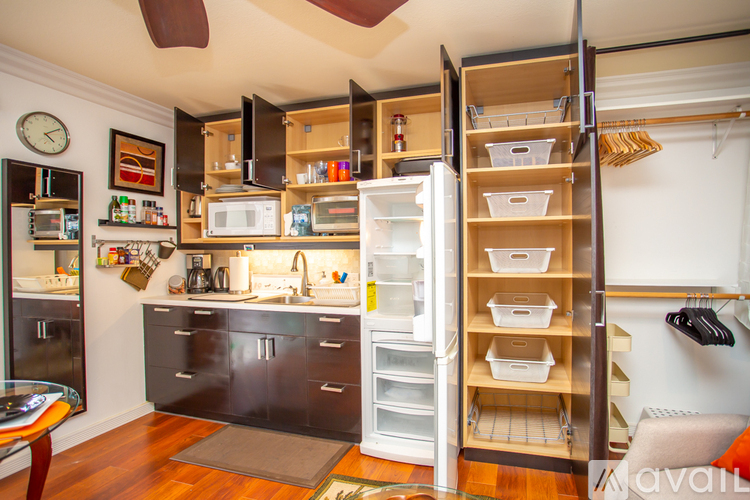 A kitchen with a refrigerator that is open and a clock on the wall.