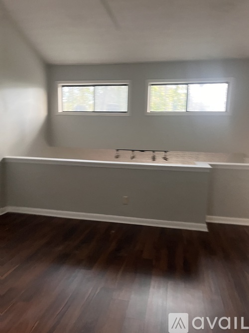 A room with wooden floors and two windows.