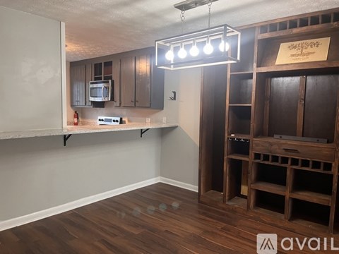 A room with wooden floors and a kitchenette with a microwave and oven.