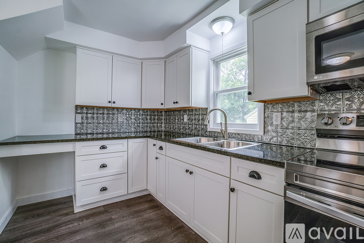 A kitchen with white cabinets and a black countertop.