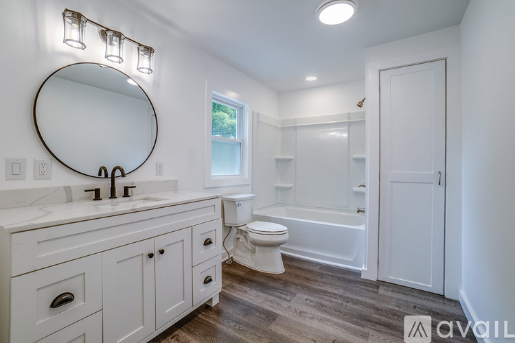 A bathroom with a white vanity and a round mirror.