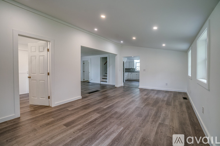 A spacious room with wooden flooring and white walls.