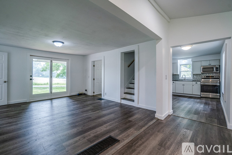 A spacious room with wooden flooring and white walls.
