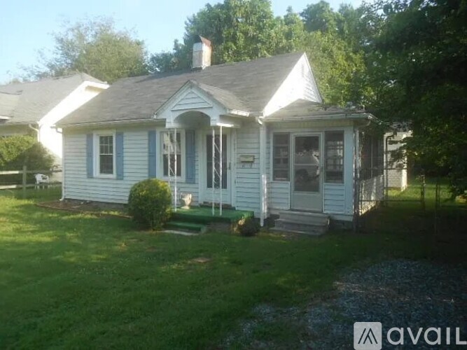 A small white house with a porch and a front yard.