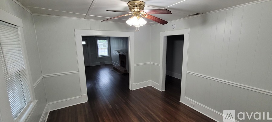 A room with a ceiling fan and wooden floors.
