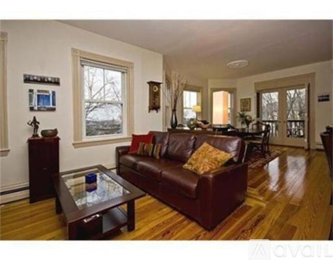A living room with a brown leather couch and a glass coffee table.