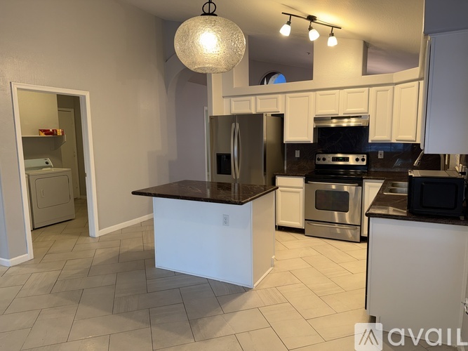 A kitchen with a black countertop and stainless steel appliances.