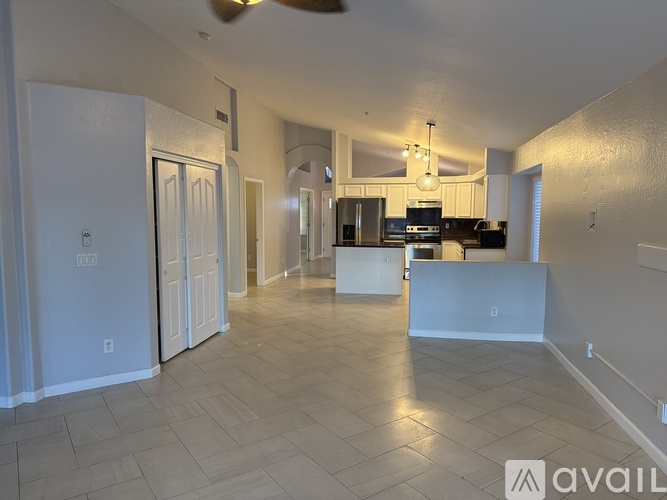 A spacious living room with a kitchen in the background.