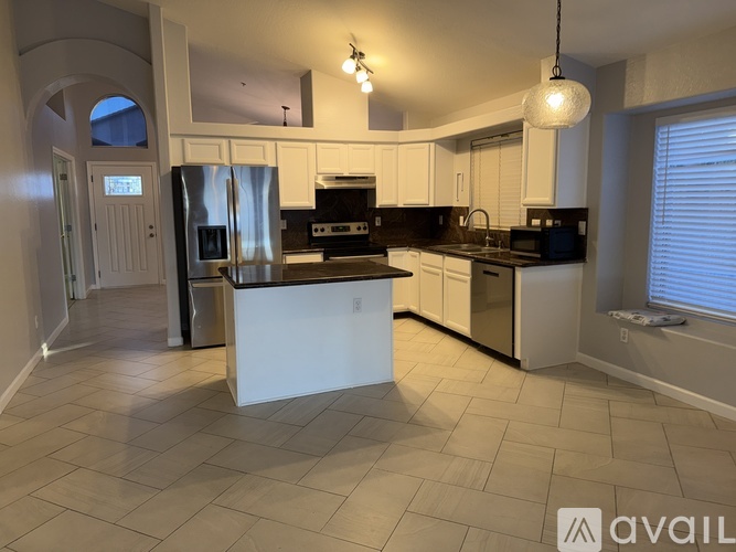 A kitchen with white cabinets and a black countertop.