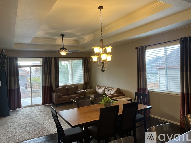 A dining room with a table set for four and a couch in the background.