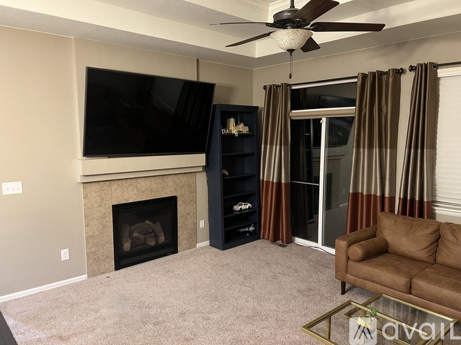 A living room with a fireplace, television, and sliding glass doors.