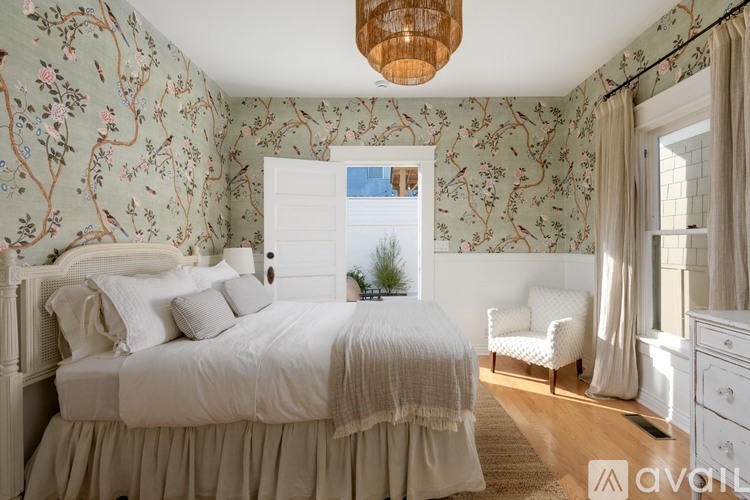 A bedroom with a large bed and a window with curtains.