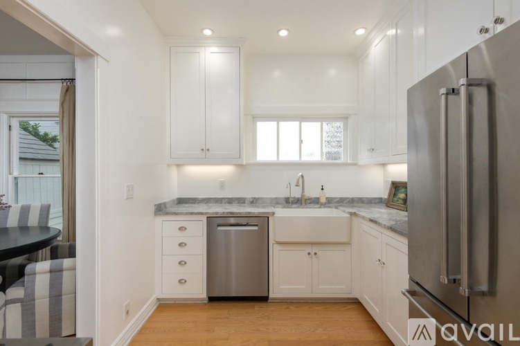A kitchen with white cabinets and a stainless steel refrigerator.