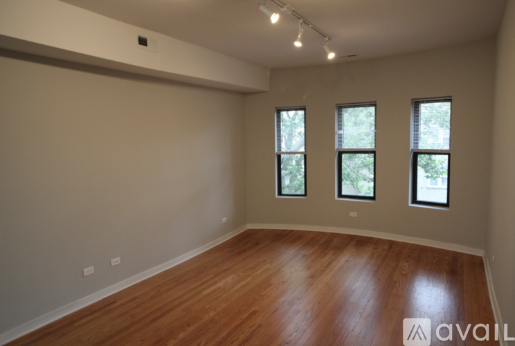 A room with wooden floors and three windows.