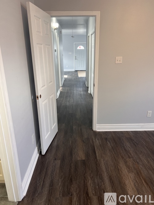 A hallway with wood floors and white walls.