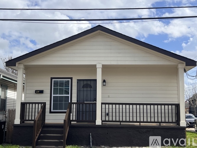 A small white house with a black railing and a sign that says "avail" on the front.