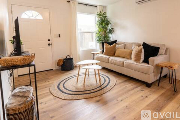 A living room with a white couch, a round rug, and a wooden floor.