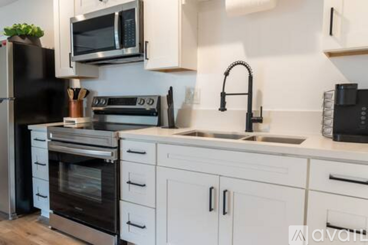 A kitchen with white cabinets and black appliances.
