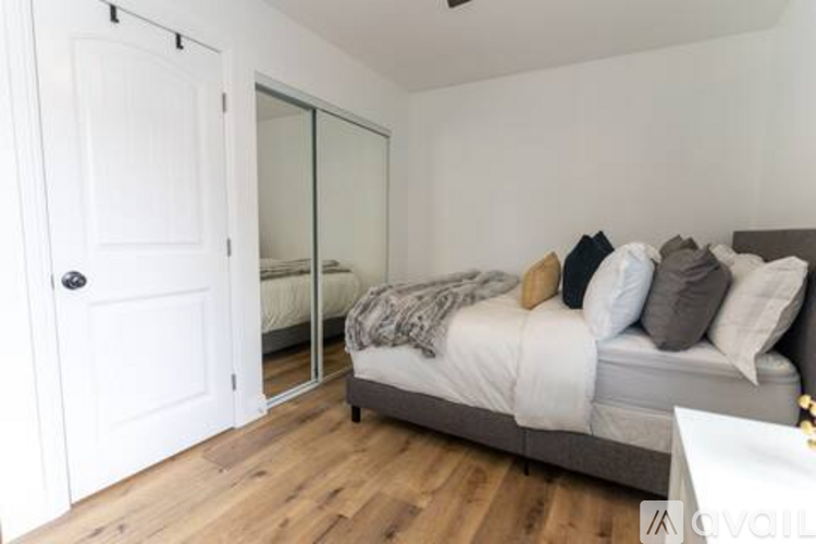 A bedroom with a bed, pillows, and a mirror.