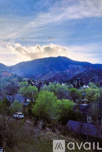 A mountain with a cloud in the sky and houses in the foreground.