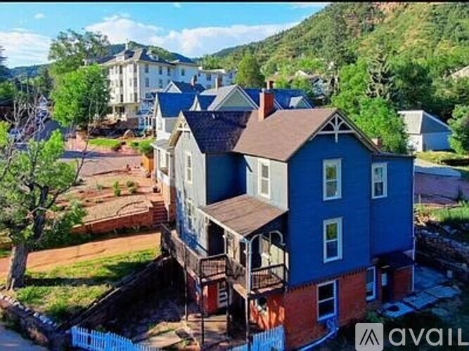 A blue house with a balcony is in the foreground with a mountain in the background.