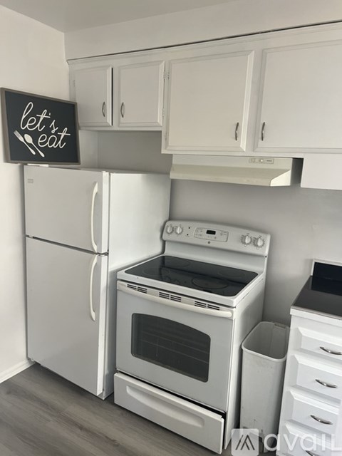 A kitchen with a white fridge, stove and cabinets with a sign that says "let's eat".