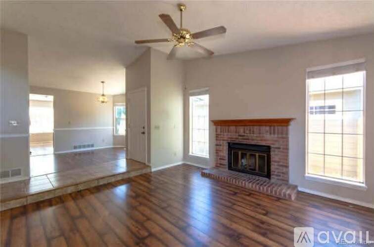 A spacious living room with wood flooring and a fireplace.