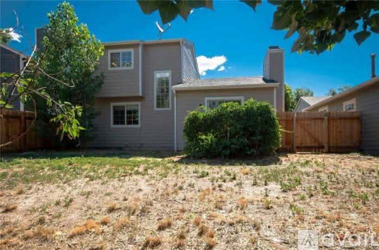 A house with a brown fence and a green tree in front.