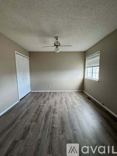 A room with a ceiling fan and wood flooring.
