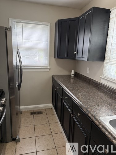 A kitchen with black cabinets and a stainless steel refrigerator.