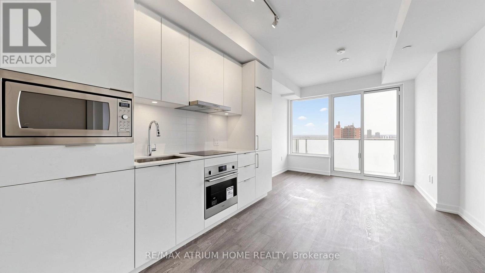 A modern kitchen with white cabinets and a microwave above the oven.