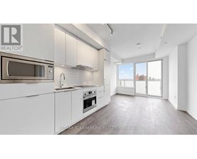 A modern kitchen with white cabinets and a microwave above the oven.