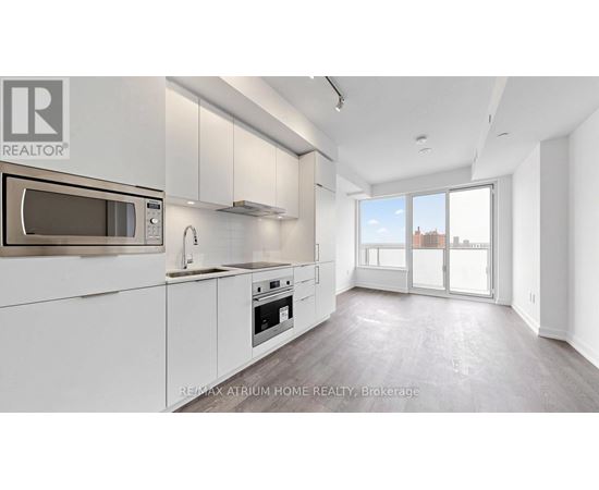 A modern kitchen with white cabinets and a microwave above the oven.