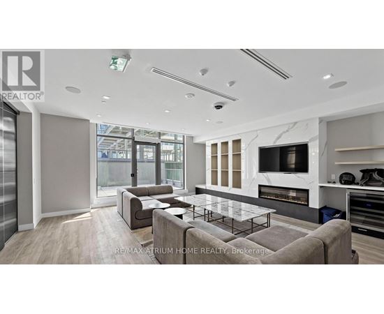 A modern living room with a glass table and a grey sofa.