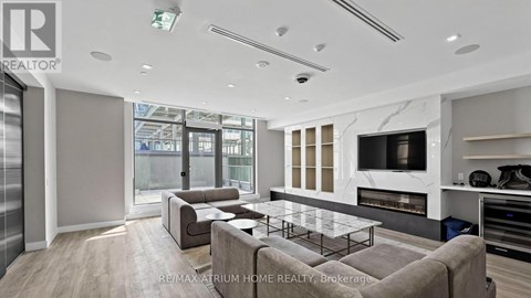 A modern living room with a glass table and a grey sofa.